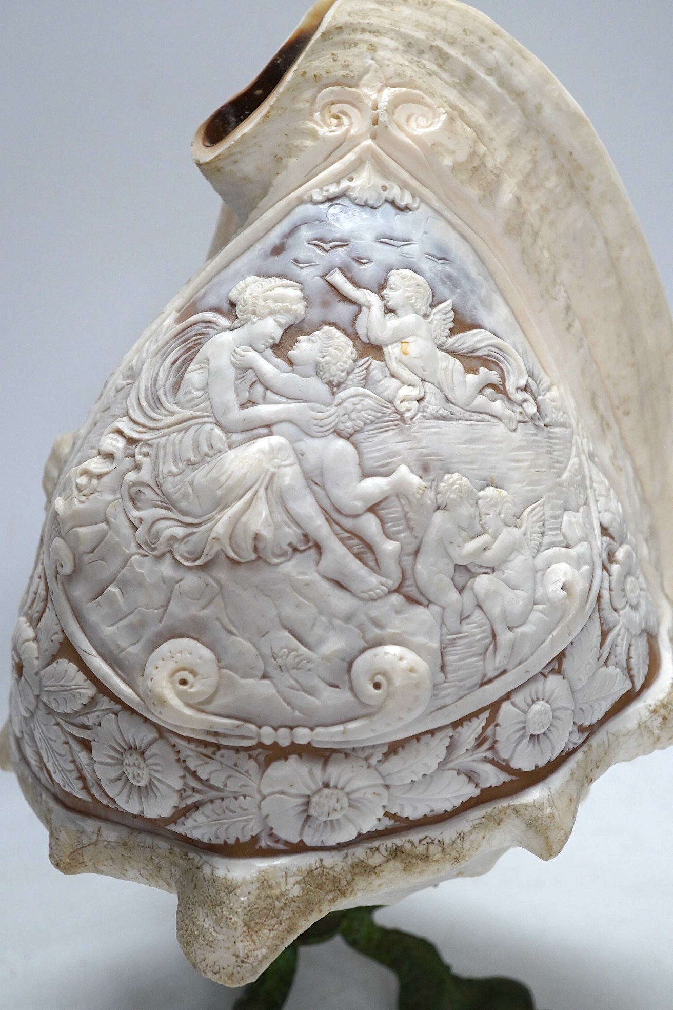 A late 19th/early 20th century large Neapolitan carved conch shell on bronze ‘dolphin’ base, height 29cm. Condition - fair, splinter chips to reverse